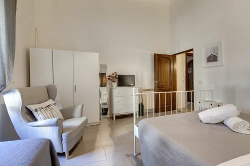 Ground floor apartment at Sleep tight Florence with bed, seating area, wardrobe and white dresser in bright neutral décor