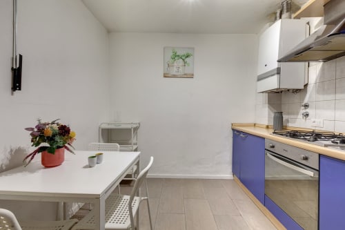 Modern kitchen in Sleep tight Florence ground floor apartment with blue cabinetry, white tiles, dining table with flowers,