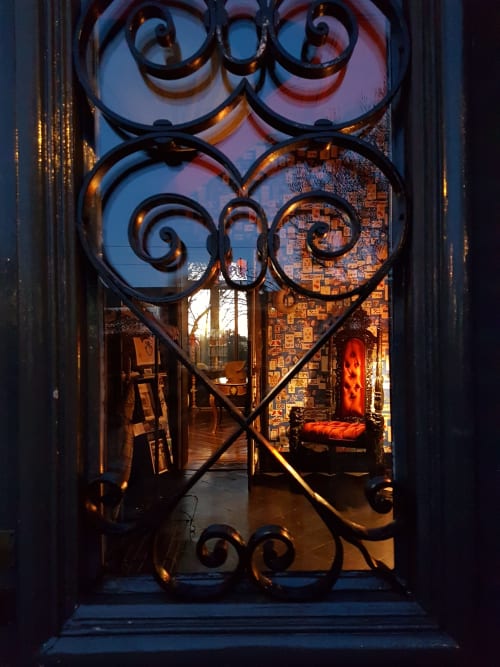 Ornate wrought iron heart-shaped gate at Le Grand Duc B&B in Valenciennes, France, opening to warm-lit interior