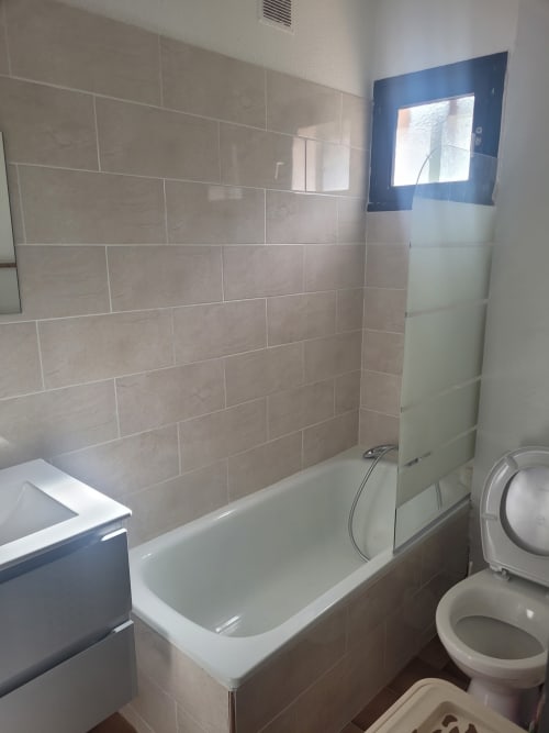 Salle de bain moderne avec baignoire, paroi de douche et toilettes dans un appartement en Corse