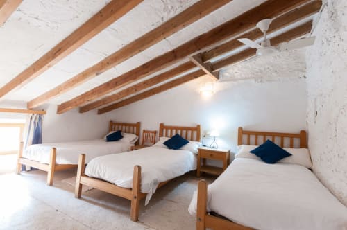 Sa Casa Rotja | Sineu, España -Este apartamento es el más grande, ideal para grupos de amigos, una gran família o dos famílias. Tiene una gran sala comedor con chimenea en la planta de abajo. Con una gran mesa para 8 personas o más. Además dispone de sofás y butacas para descansar. En la planta superior está la cocina con todo lo necesario para cocinar y comer, la terraza privada con vistas al patio, el baño completo y las tres habitaciones. En cada habitación hay dos camas individuales.