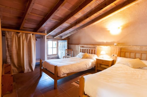 Sa Casa Rotja | Sineu, España -Este apartamento es el más grande, ideal para grupos de amigos, una gran família o dos famílias. Tiene una gran sala comedor con chimenea en la planta de abajo. Con una gran mesa para 8 personas o más. Además dispone de sofás y butacas para descansar. En la planta superior está la cocina con todo lo necesario para cocinar y comer, la terraza privada con vistas al patio, el baño completo y las tres habitaciones. En cada habitación hay dos camas individuales.