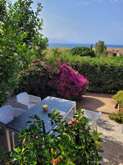 Terrasse côtière à Ajaccio en Corse avec bougainvillée fuchsia, table de salle à manger et vue sur la mer Méditerranée