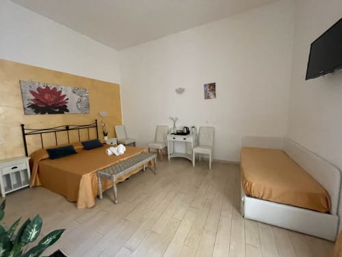 Camera spaziosa presso AD Trastevere Guest House Roma con letto matrimoniale, letto singolo, scrivania bianca e parete in oro-giallo