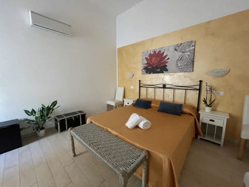 Camera luminosa con pareti dorate, letto in ferro e servizi moderni presso l'AD Trastevere Guest House di Roma