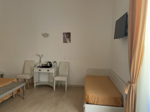 Accogliente camera per gli ospiti presso AD Trastevere a Roma con letto, scrivania, sedie e TV a parete