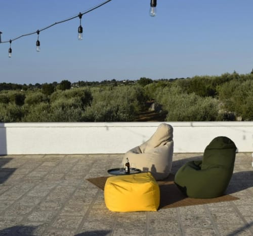 Terrazza esterna di Casa Ziazì con sedute a pouf, luci decorative e vista sul frutteto di ulivi a Monopoli