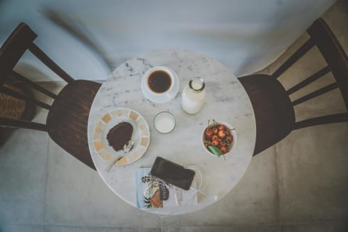 Vista dall'alto del tavolo in marmo di Casa Ziazì con caffè, latte, pasticcini e fragole fresche a Monopoli