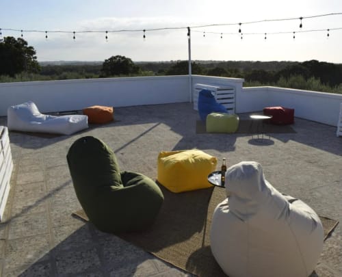 Lounge sulla terrazza di Casa Ziazì con coloratissimi pouf, luci decorative e vista panoramica sulla campagna di Monopoli