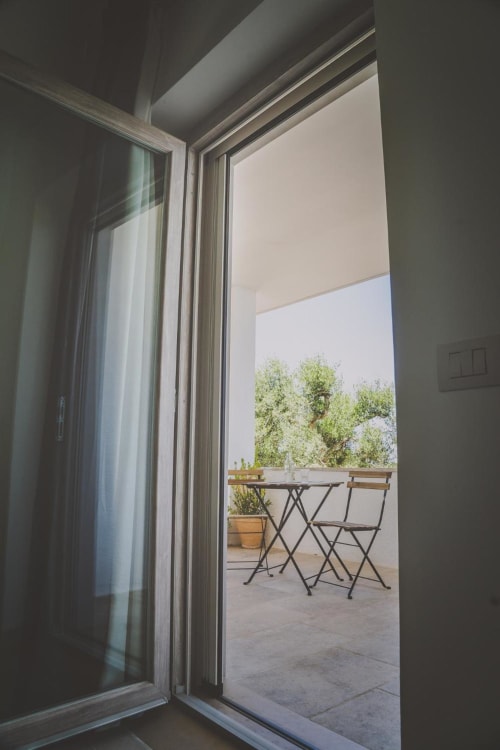 Porte in vetro aperte che rivelano un balcone con tavolo e sedie a Casa Ziazì a Monopoli