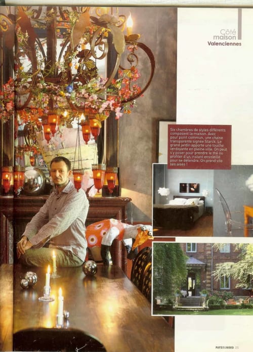 Homme dans la salle à manger du boutique-hôtel Le Grand Duc à Valenciennes, avec un lustre ornementé et des lanternes rouges