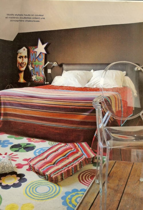 Colorful bedroom at Le Grand Duc B&B in Valenciennes with striped bedding, whimsical wall art, and vibrant geometric rug