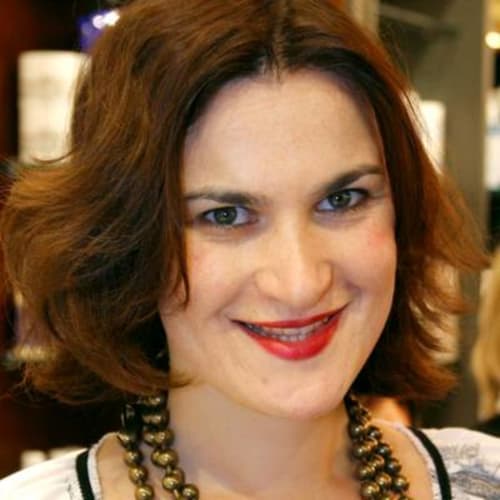 Smiling woman with reddish-brown hair and red lipstick at Le Grand Duc boutique hotel in Valenciennes, France