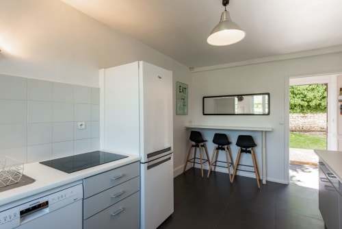 Modern kitchen with bar seating at Les Maisons de Chamirey BnB in Mercurey, France, opening to garden views