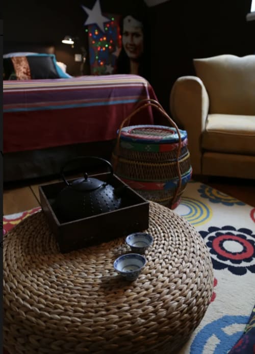 Cozy living room at Le Grand Duc B&B Valenciennes with woven round table, Asian tea set, colorful decor and festive Christmas