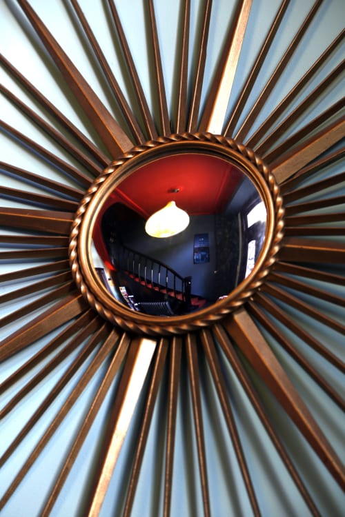 Miroir soleil décoratif reflétant le plafond rouge de la chambre au gîte Le Grand Duc, Valenciennes