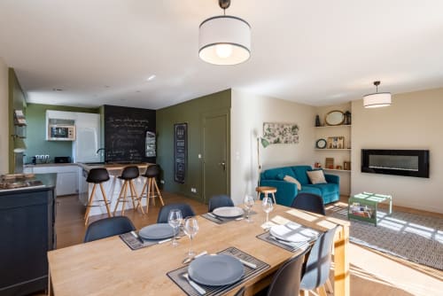 Modern open-plan living space at Les Maisons de Chamirey in Mercurey with dining table, turquoise sofa, kitchen, and