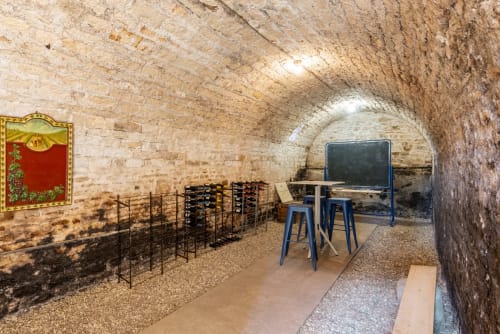 Historic stone wine cellar at Les Maisons de Chamirey in Mercurey with blue chair, table, and blackboard for wine tastings