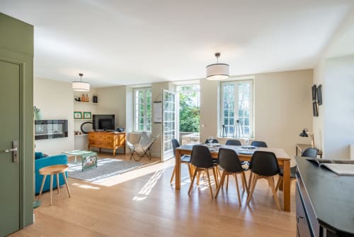 Modern open-plan living space at Les Maisons de Chamirey with dining table, workspace, and lounging area overlooking