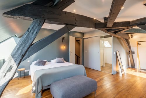 Spacious bedroom with exposed wooden beams at Les Maisons de Chamirey, featuring bed, wooden floors, and modern amenities in