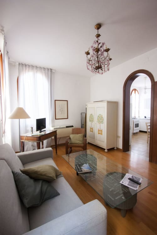 Elegant living room at Ca Cortigiane in Venice with sofa, desk, chandelier, and arched doorway