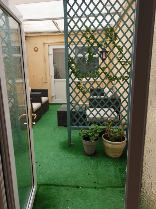 Balcony at The Sands Hotel Paignton with artificial grass, green lattice trellis, climbing plants, and wicker furniture