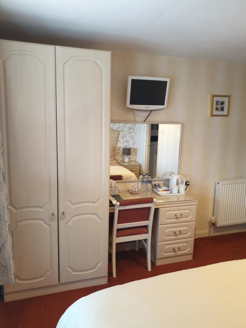 Hotel bedroom at The Sands Hotel in Paignton with cream wardrobe, dressing table, mirror, and wall-mounted TV