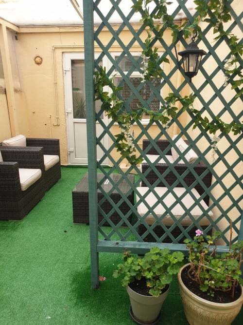 The Sands Hotel courtyard patio in Paignton with green artificial turf, wicker seating, lattice trellis with climbing ivy,
