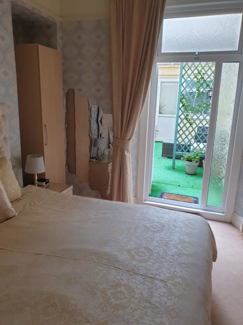 Modern hotel bedroom at The Sands Hotel, Paignton, with bed, wardrobe, and patio doors overlooking garden