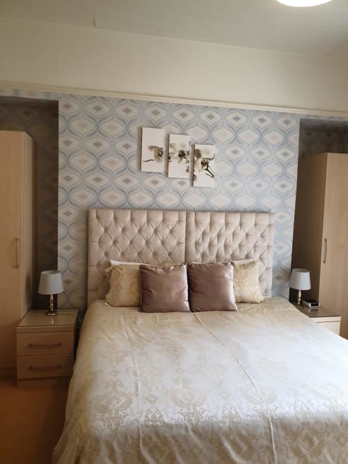 Elegant bedroom at The Sands Hotel in Paignton with quilted headboard, cream bedding, and patterned wallpaper