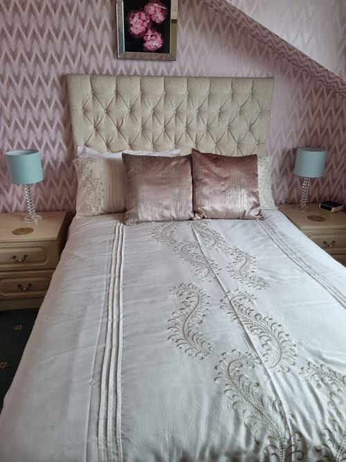 Elegant bedroom at The Sands Hotel Paignton with cream quilted headboard, white bedding, burgundy pillows, and pink patterned
