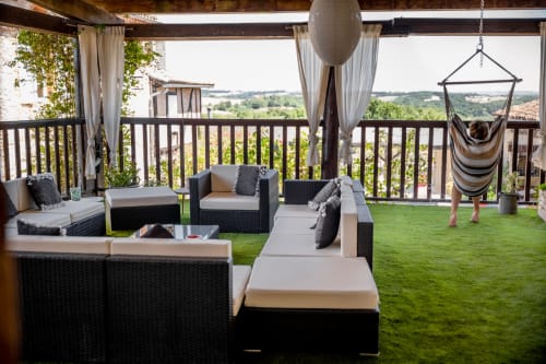 Luxury terrace at Le Pignié with wicker seating, hammock chair, and panoramic views of Lescure-d'Albigeois countryside