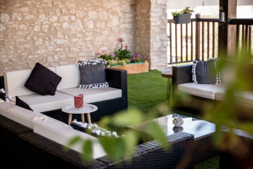 Modern outdoor patio at Le Pignié B&B in Lescure-d'Albigeois with black and white seating, potted flowers, and stone walls