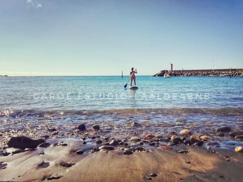 A person paddle surfing on the beach of La Aldea