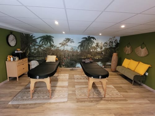 Spa treatment room at Pavillon Des Millesimes with massage beds, tropical mural, green walls, and natural wood furnishings.