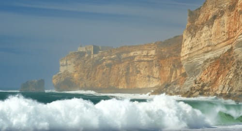 vue sur la falaise et le phare depuis la plage de Nazaré