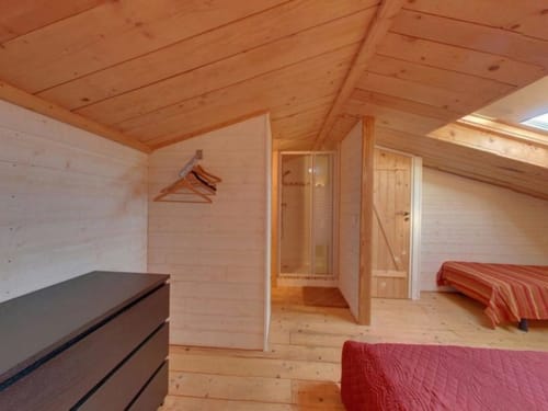 Chambre mansardée en bois à la villa Le Maquis Plage avec deux lits, commode et salle de bain privative à Poggio-Mezzana