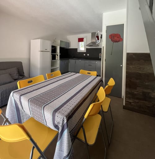 Salle à manger de villa moderne avec chaises jaunes, cuisine et chambre à Le Maquis Plage, Corse
