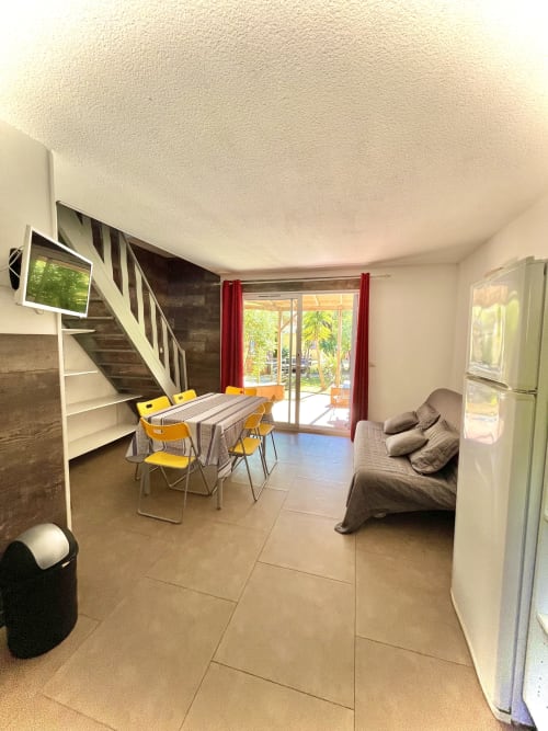 Espace de vie ouvert de la villa Le Maquis Plage avec table à manger, canapé, cuisine et escaliers vers l'étage
