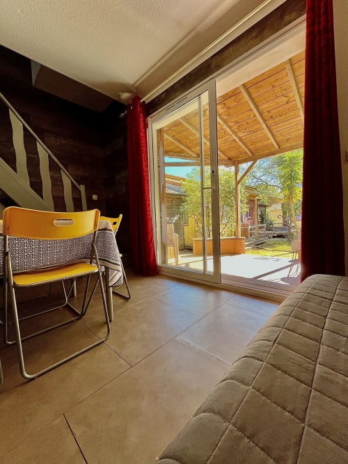 Chambre de villa avec fauteuil jaune, portes-fenêtres donnant sur le jardin à Le Maquis Plage, Poggio-Mezzana
