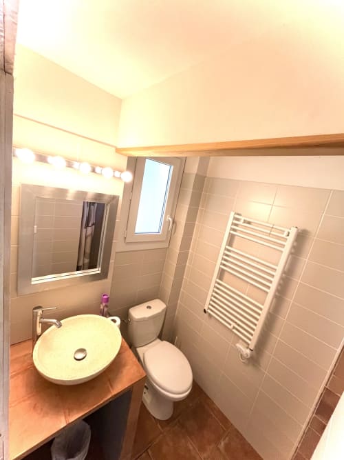 Salle de bains moderne de la villa Le Maquis Plage avec vasque ronde, toilettes, sèche-serviettes chauffant et miroir éclairé