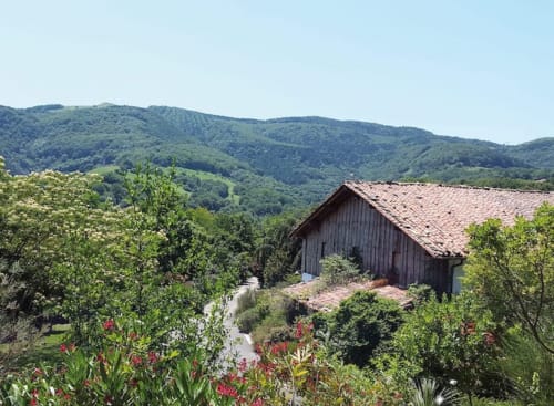 Caserío vasco rural con tejado de barro anidado en verdes colinas de Casa rural MAÑARINEGI, Gipuzkoa