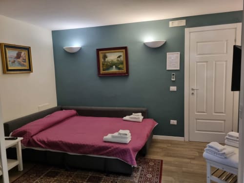 Superior Suite 202 at B&B Il Conservatorio in Naples, featuring teal walls, burgundy bedding, and garden views