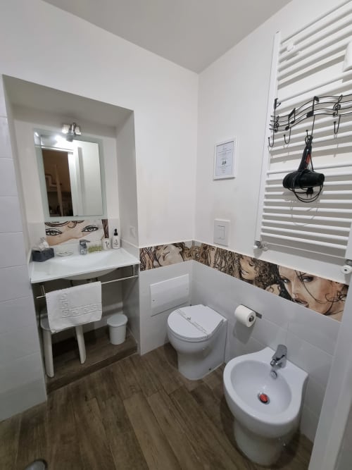 Modern bathroom in B&B Il Conservatorio Naples with vanity mirror, toilet, bidet, wooden flooring, and portrait tile