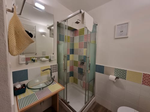 Modern bathroom in Junior Suite at B&B Il Conservatorio, Naples, featuring colorful patterned tiles, glass shower enclosure,