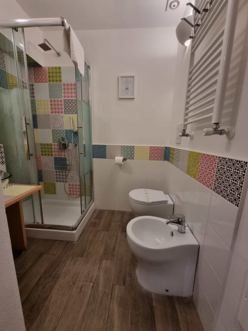Modern bathroom in Junior Suite 203 at B&B Il Conservatorio, Naples featuring colorful patchwork tile shower, bidet, sink,