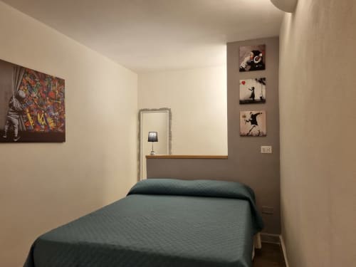 Modern bedroom in Il Conservatorio B&B Naples with dark green bed, Banksy-style artwork, and contemporary wall decor