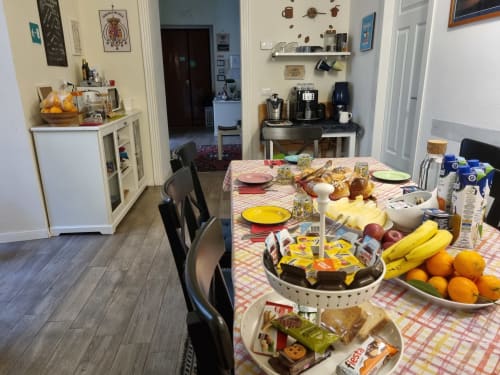 Desayuno en el B&B Il Conservatorio de Nápoles con frutas frescas, pastelería y cubiertos sobre mantel a cuadros