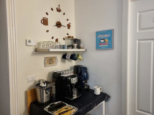 Rincón de café en B&B Il Conservatorio Nápoles con reloj de pared temático, tazas y letrero de desayuno