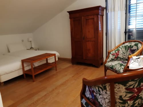 Spacious twin bedroom at Casa Rural La Perla with wooden furniture, hardwood floors, balcony access, and garden views in